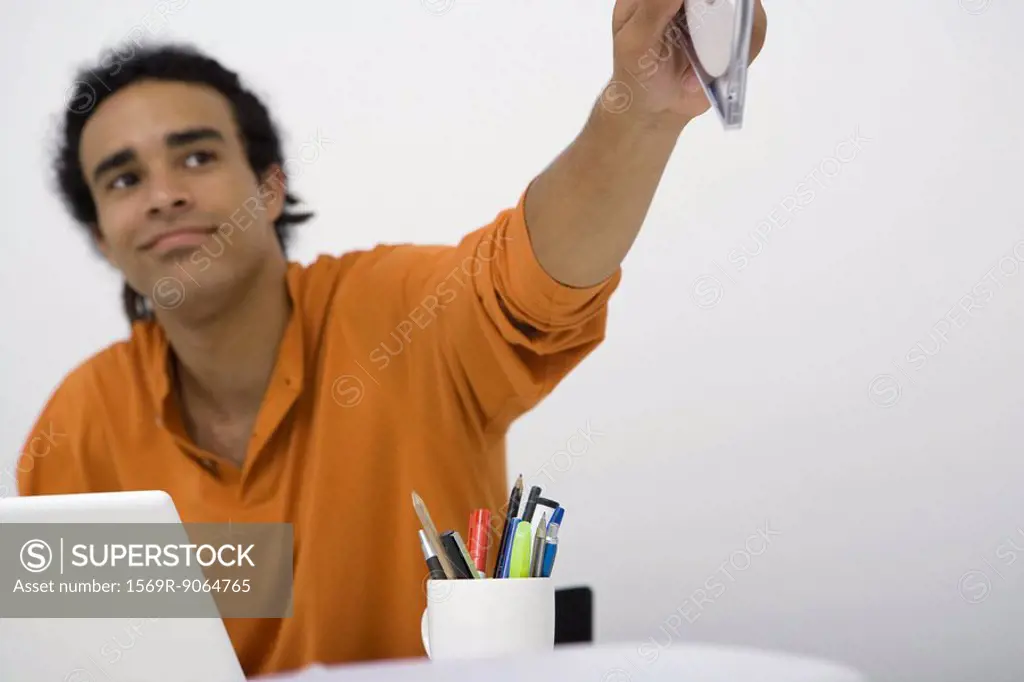 Man sitting at desk, holding out CD