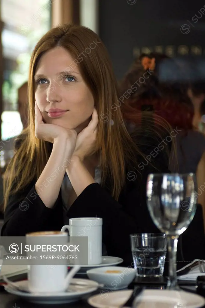 Woman sitting in cafe, daydreaming