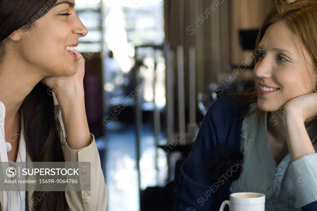 Two female friends having coffee and chatting in cafe