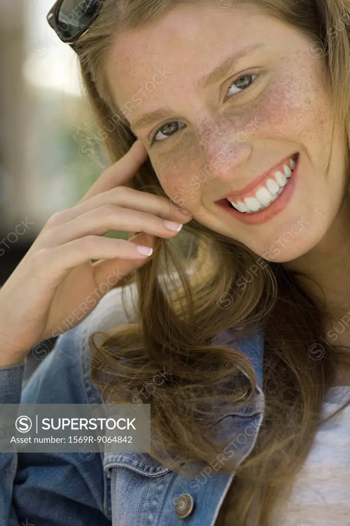 Young woman with freckles smiling at camera, portrait