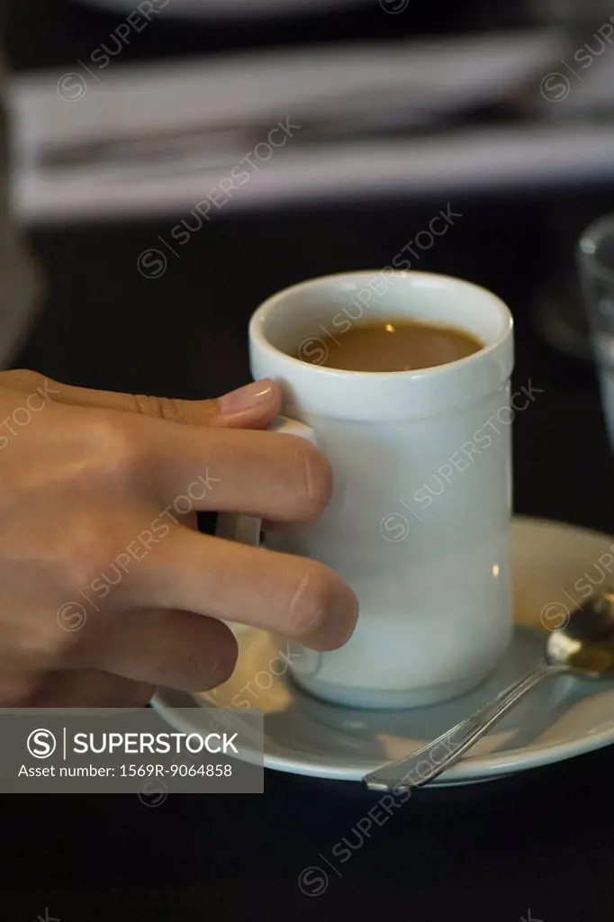 Woman´s hand picking up cup of coffee, close-up