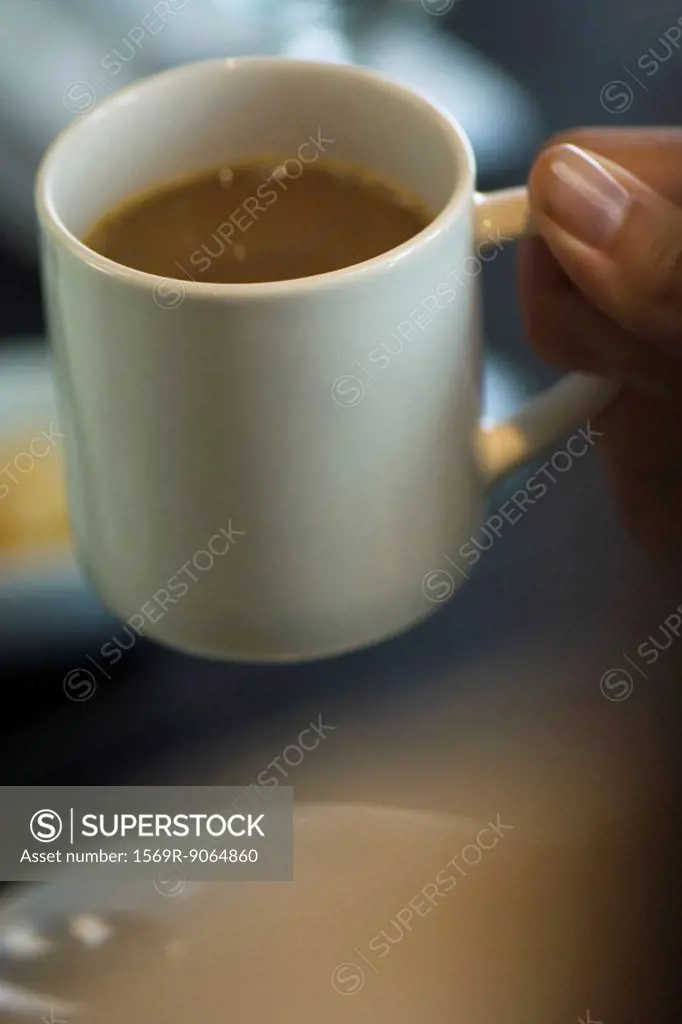 Hand picking up mug of coffee