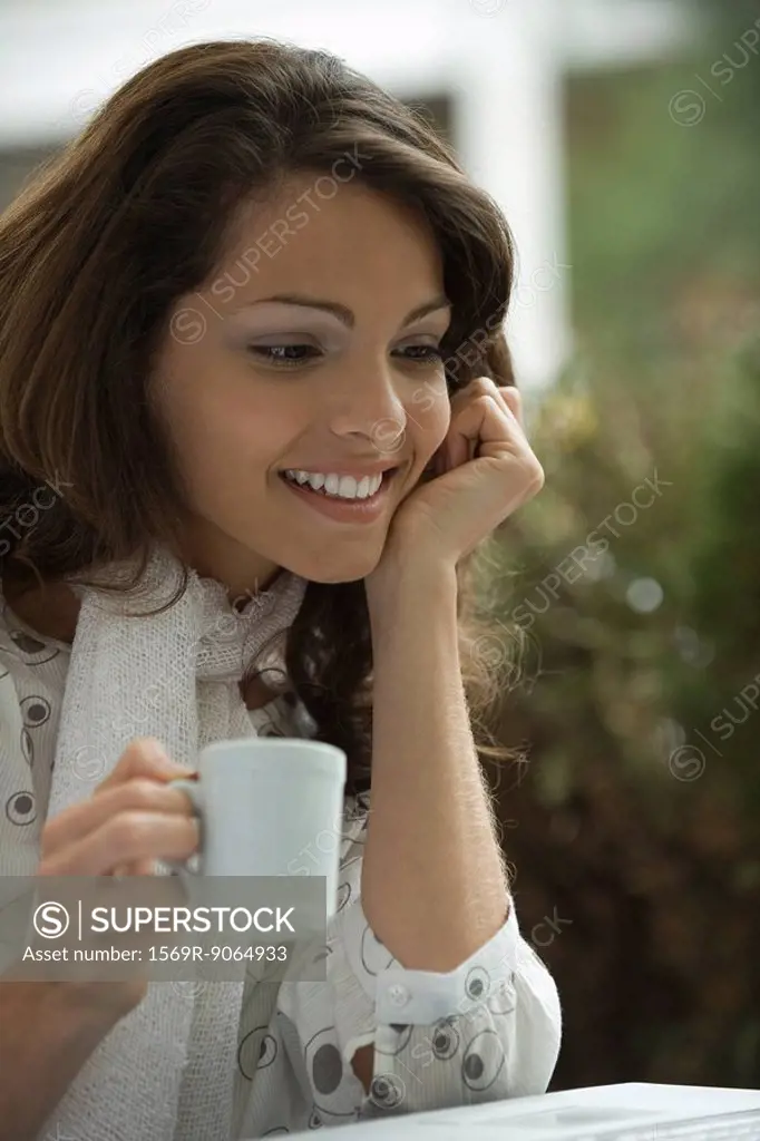 Young woman drinking coffee and looking at laptop computer