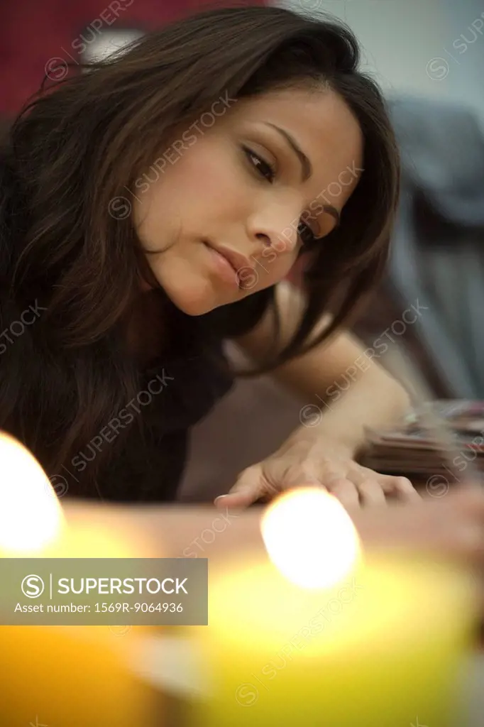 Woman writing, candles burning in foreground