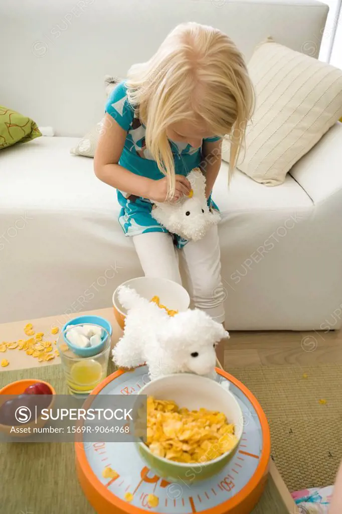 Little girl feeding cereal to stuffed toy