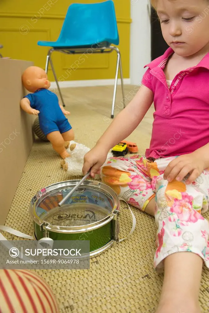 Little girl playing toy drum