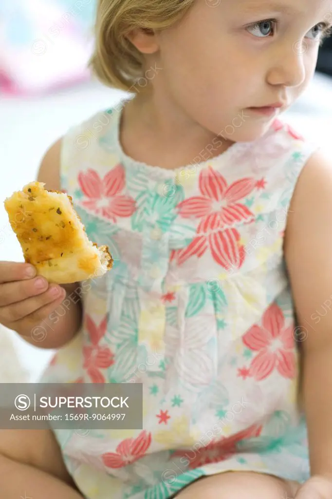 Little girl eating bread, looking away