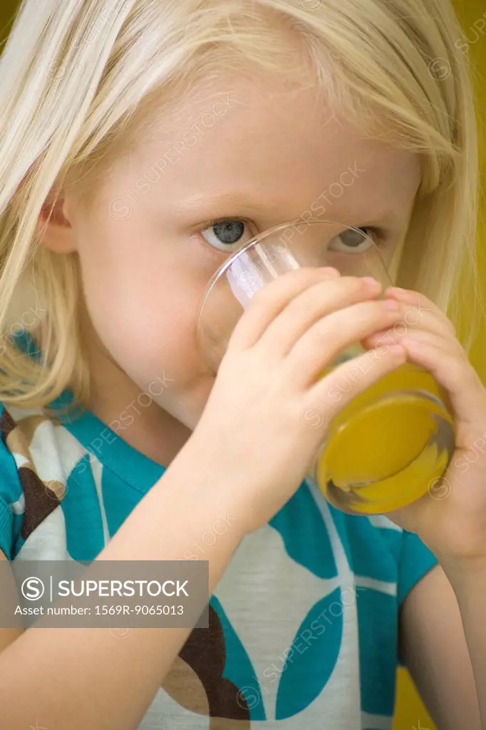 Little girl drinking glass of juice, close-up