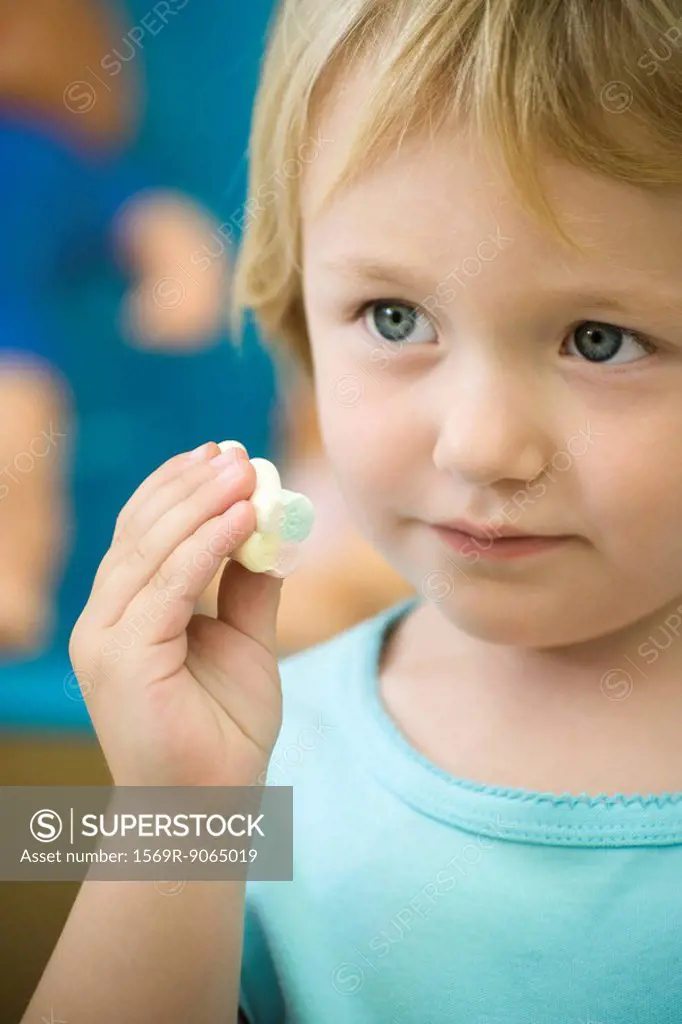 Little girl holding marshmallow, close-up