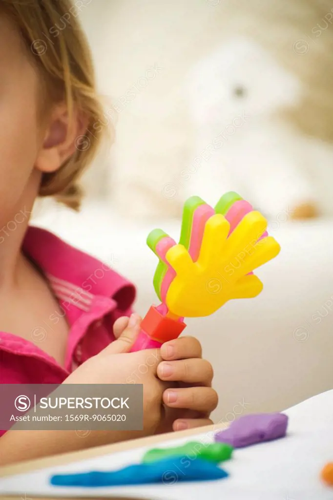 Little girl holding plastic clapping toy, cropped view