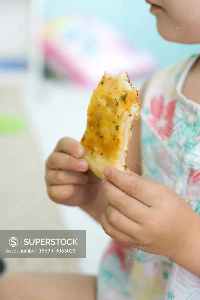 Child eating slice of pizza, cropped view