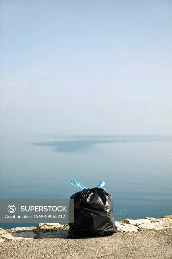 Garbage bag on ledge with sea in background