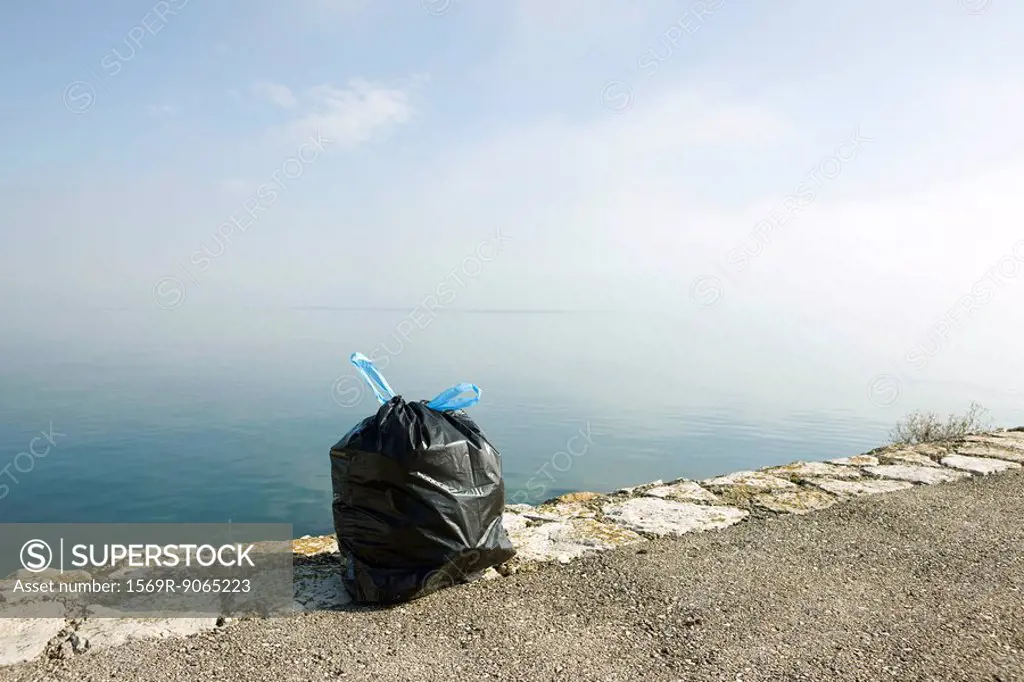 Garbage bag on ledge with sea in background