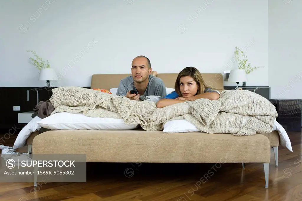 Couple lying in bed watching television