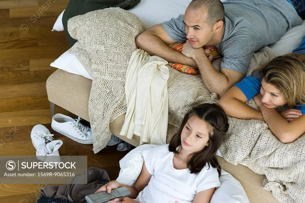 Family lying in bed watching television, directly above