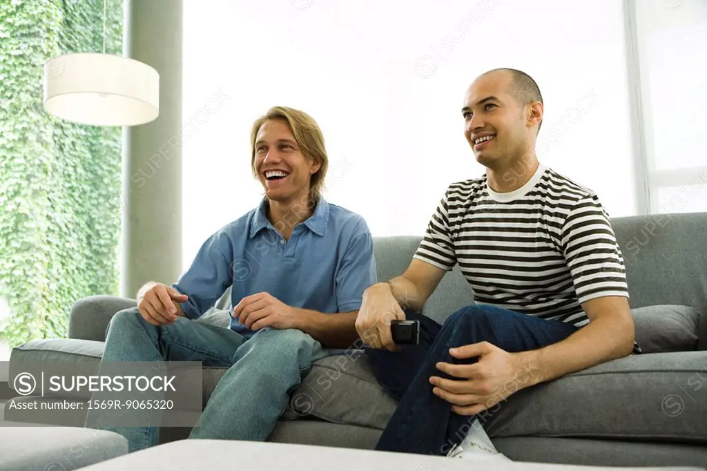 Two men watching TV on sofa