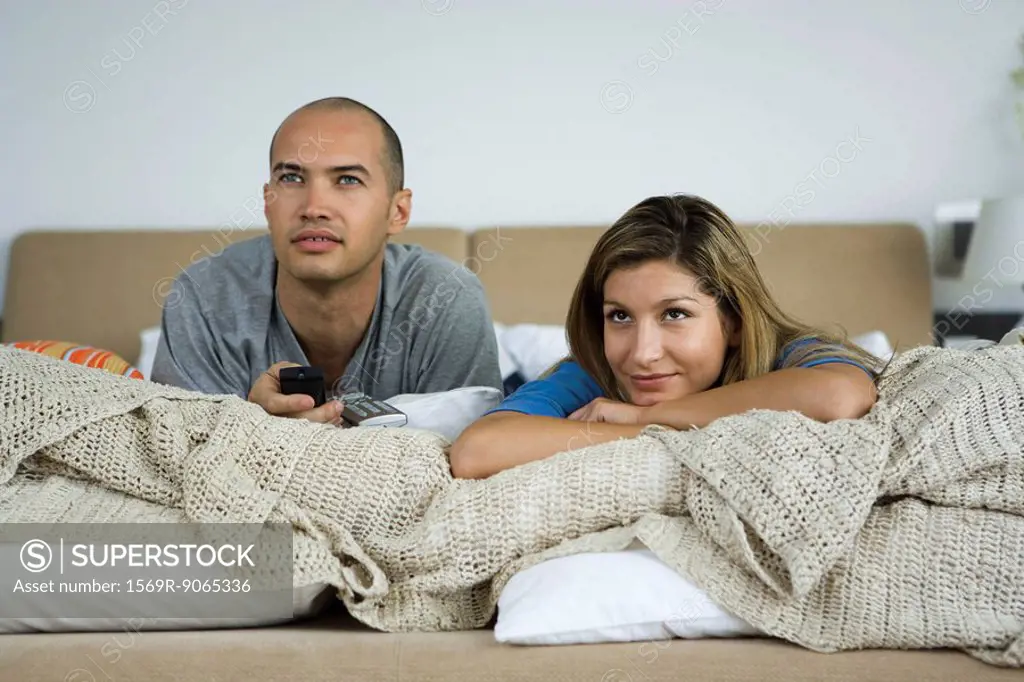 Couple lying on bed watching TV together