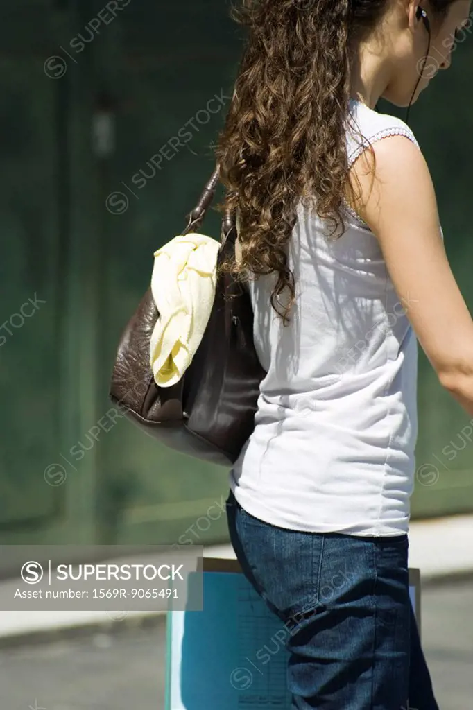 Casually dressed female carrying purse and documents, side view