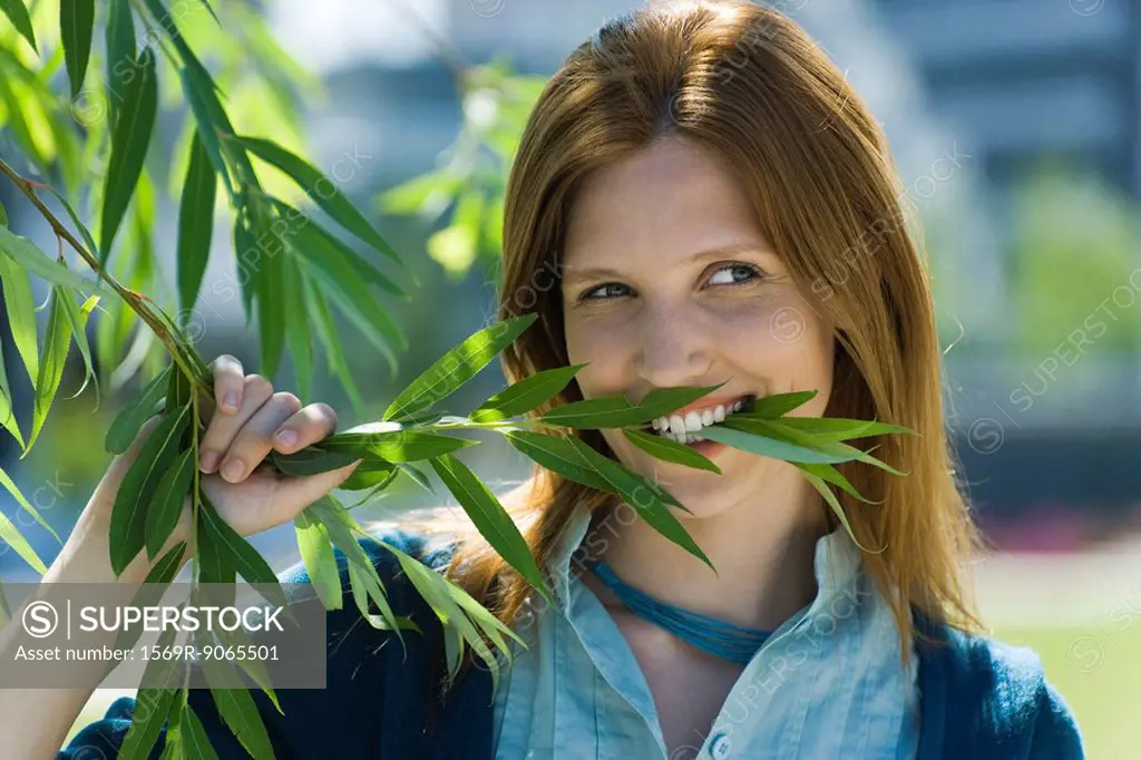 Young woman holding branch in teeth, portrait
