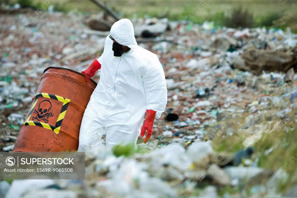 Person in protective suit carrying barrel of hazardous waste