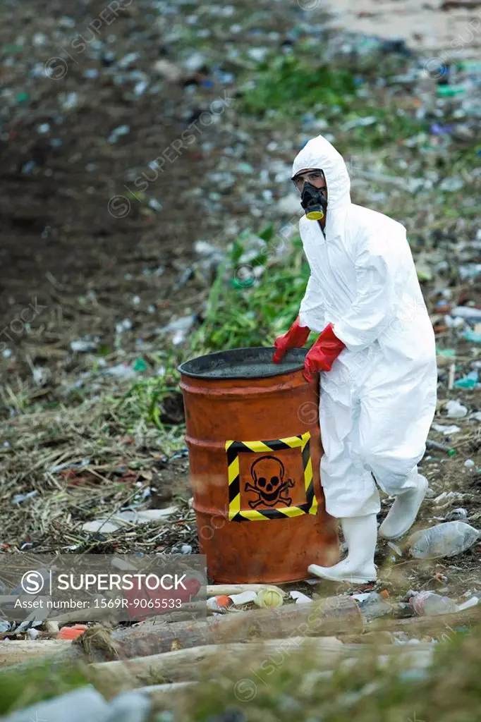 Person in protective suit carrying barrel of hazardous waste