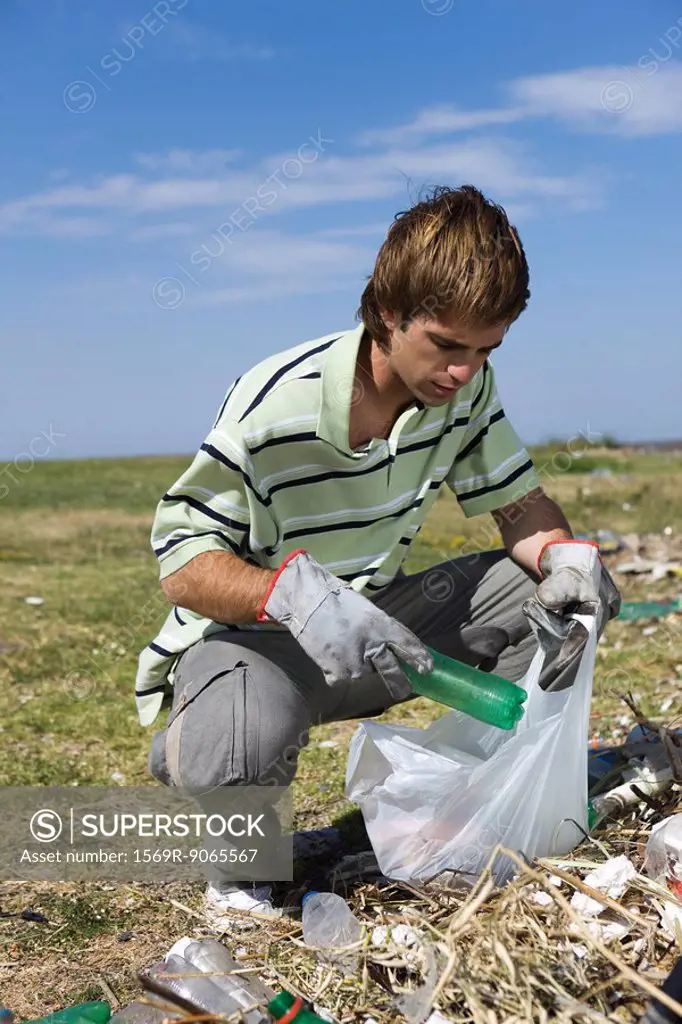 Male picking up trash in field