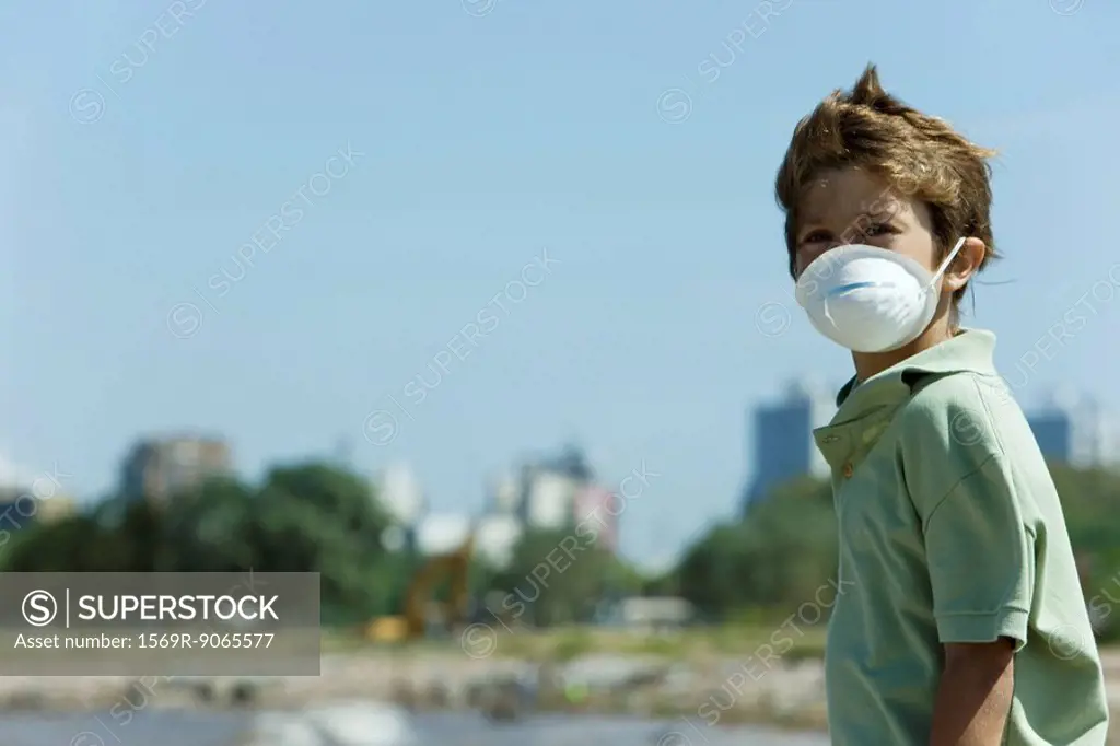 Boy standing outdoors, wearing pollution mask