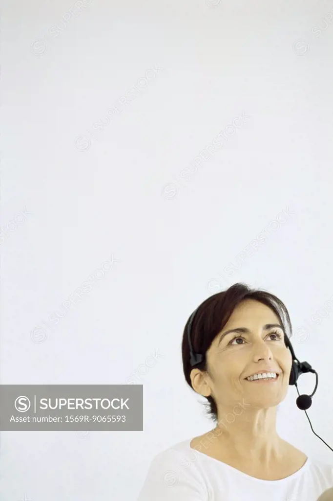 Mature woman wearing phone headset, smiling, looking up