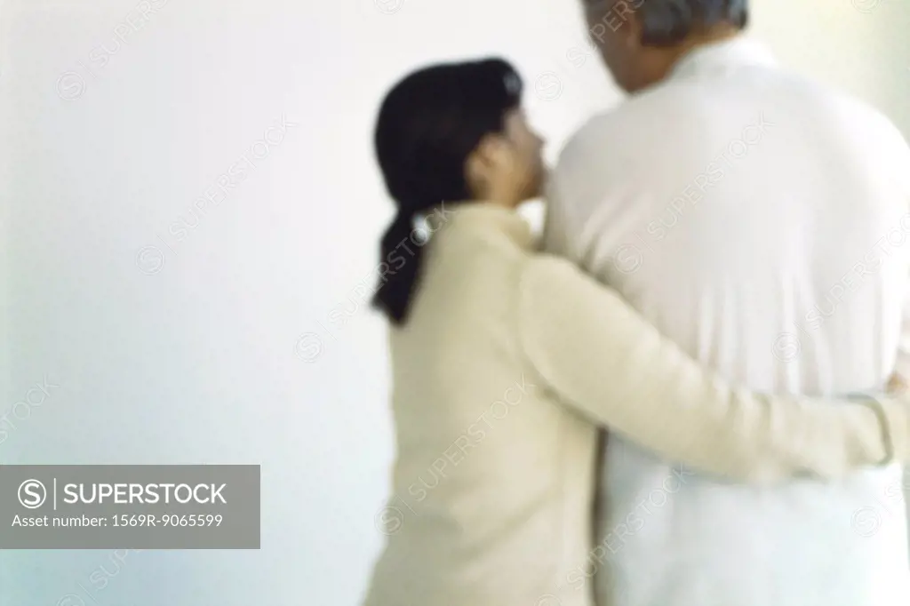 Woman embracing husband, displaying concern, rear view