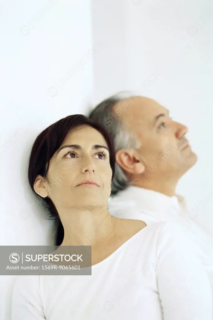 Man and woman sitting, leaning against each other looking away