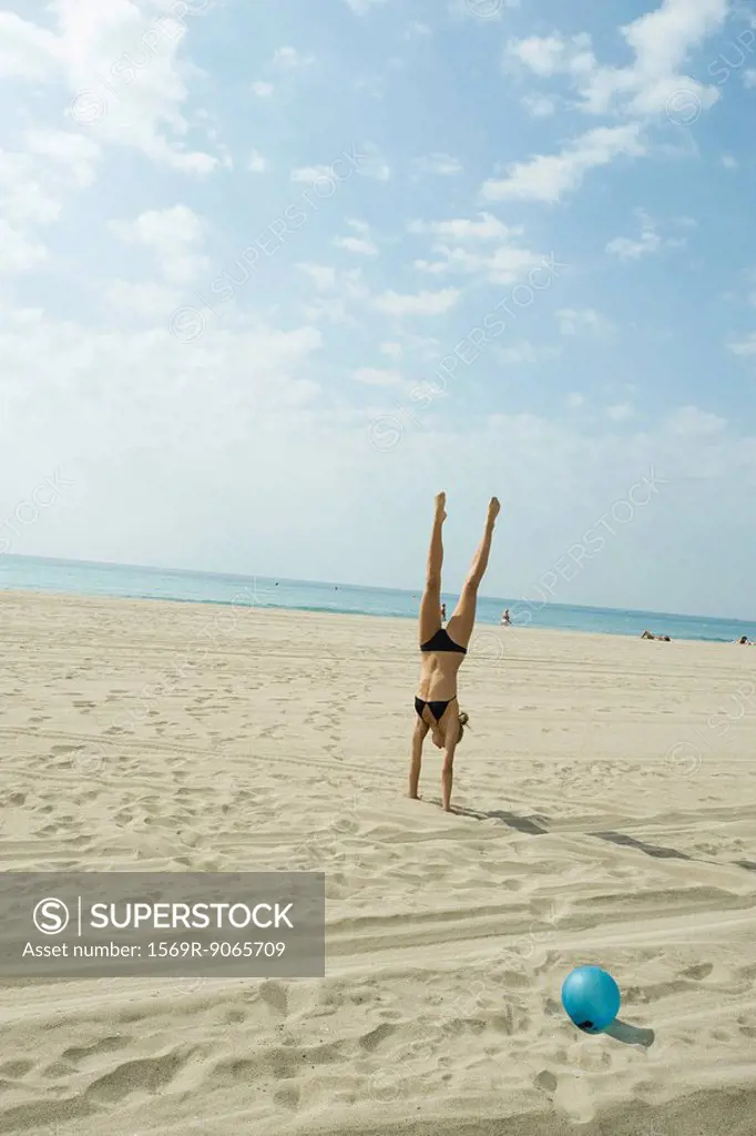 Teen girl doing handstand on beach