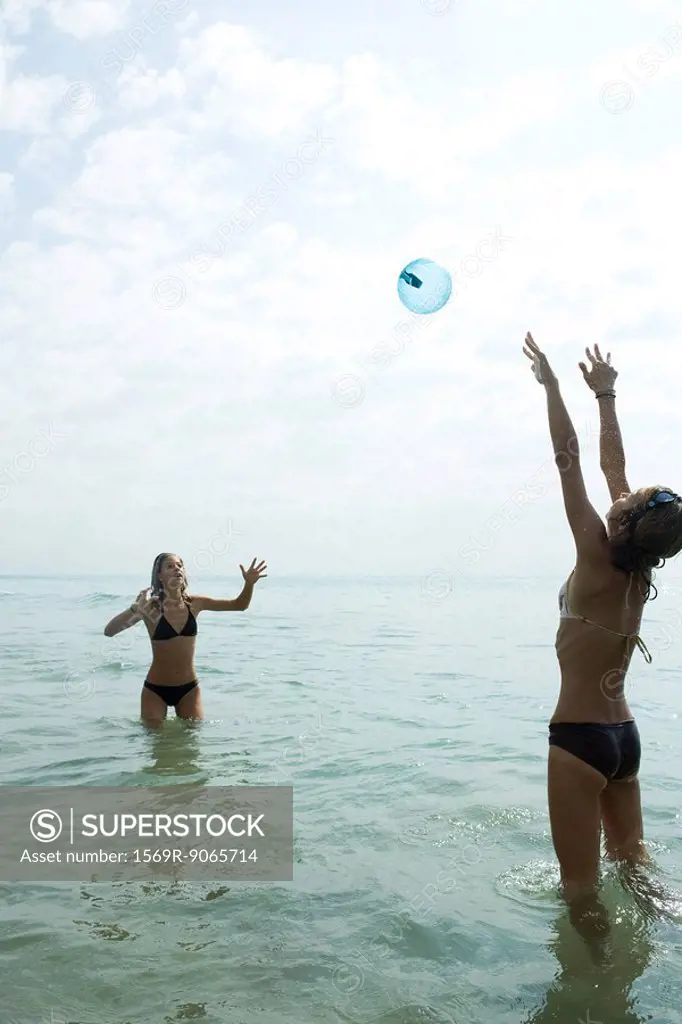 Teen friends waist deep in water playing with beach ball