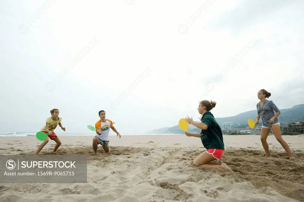 Teen friends playing paddleball on beach