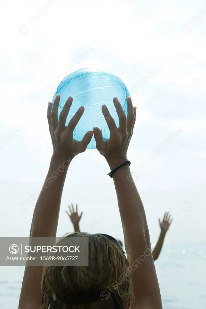 Teen girl catching ball with arms raised, cropped