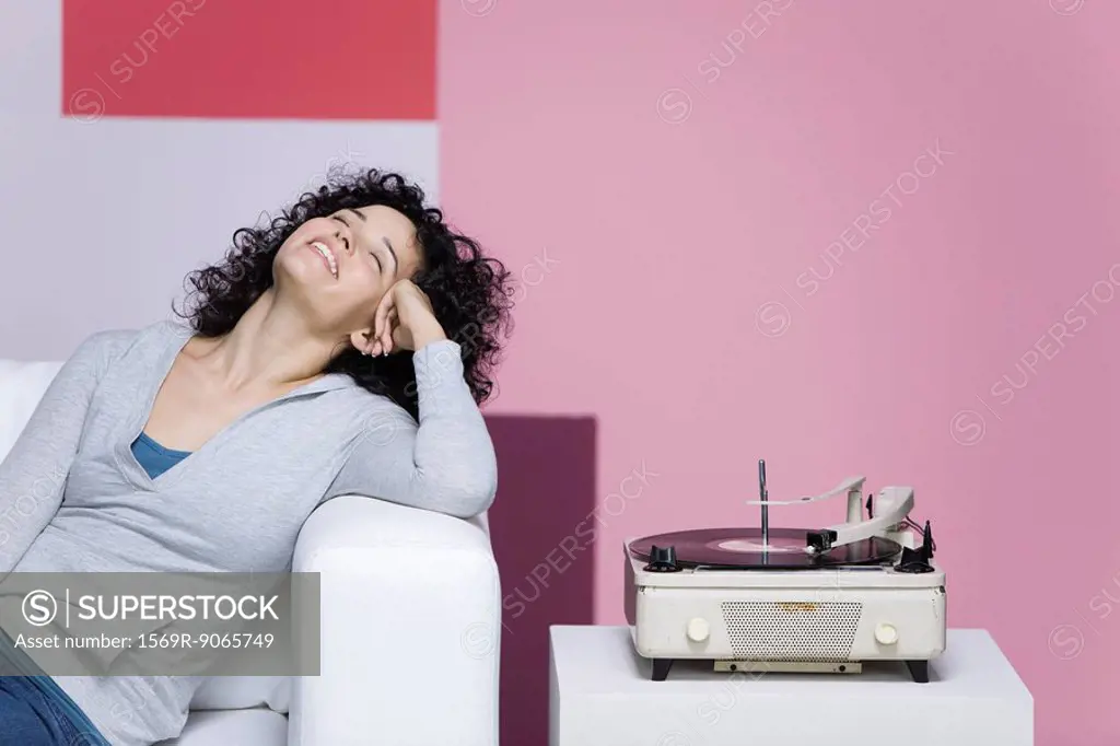 Woman enjoying music, listening to old-fashioned record player