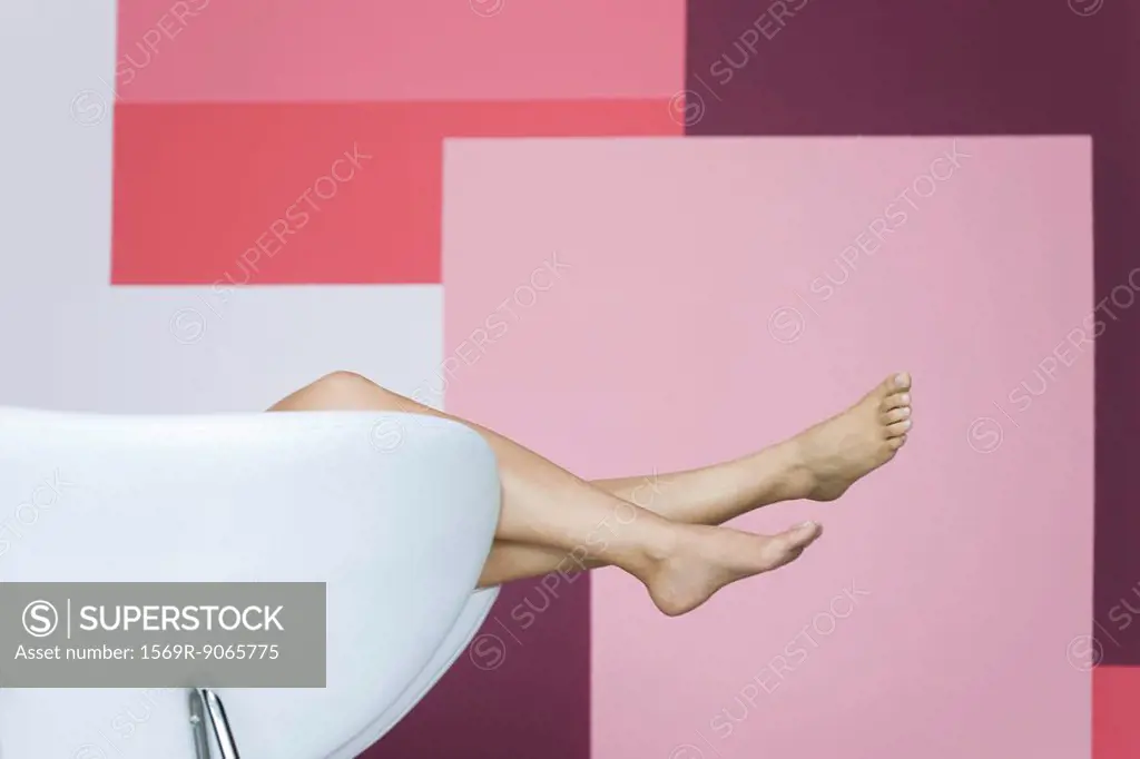 Woman reclining on armchair, cropped view of bare legs