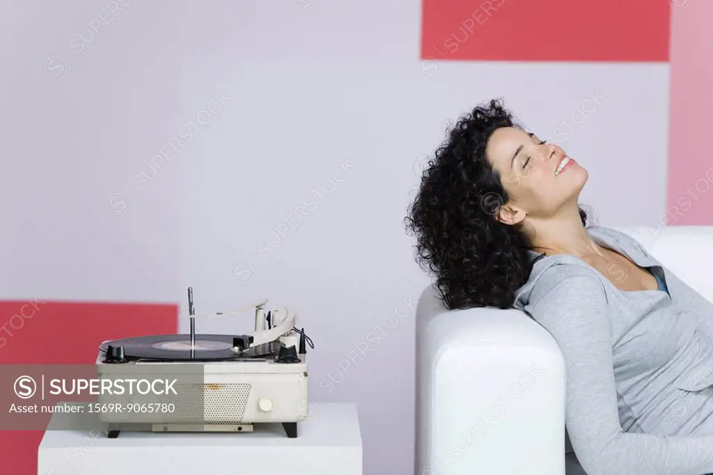 Woman enjoying music, listening to old-fashioned record player