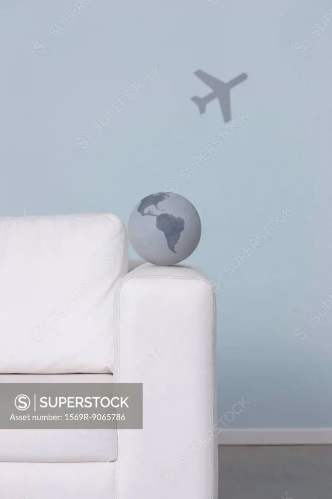 Globe on arm of sofa, airplane in background