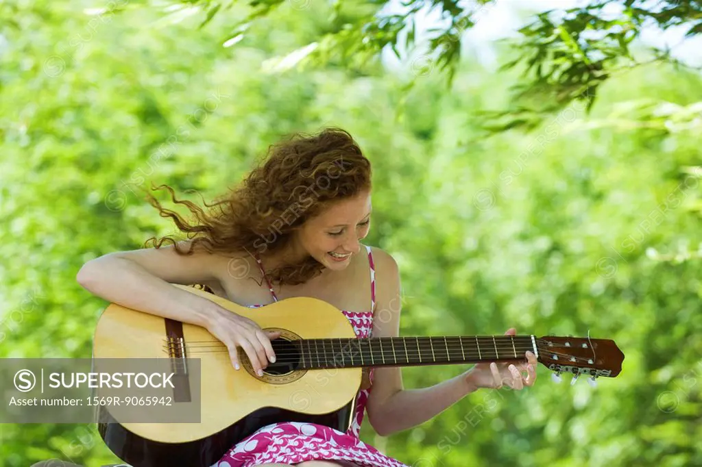 Young woman playing acoustic guitar outdoors