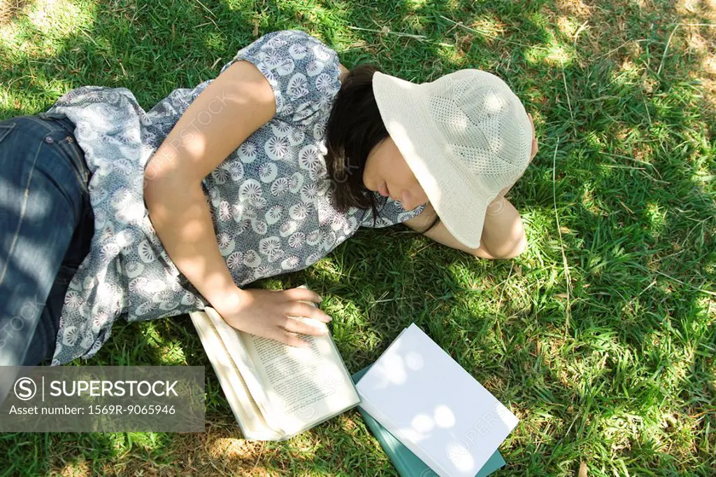 Young woman lying on the ground reading, high angle view