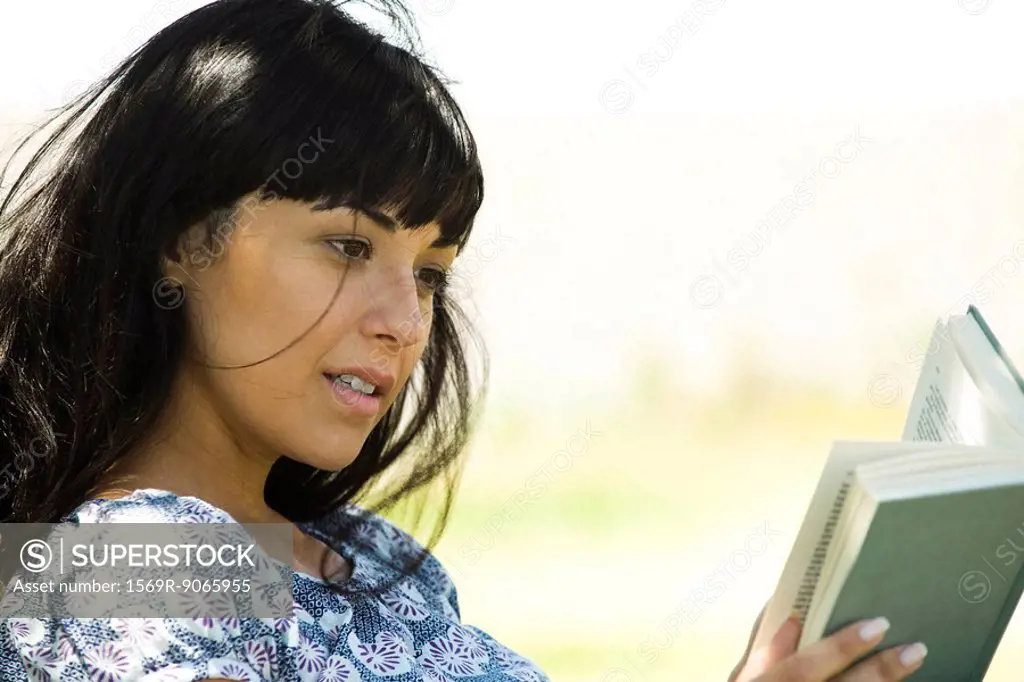 Young woman reading book outdoors