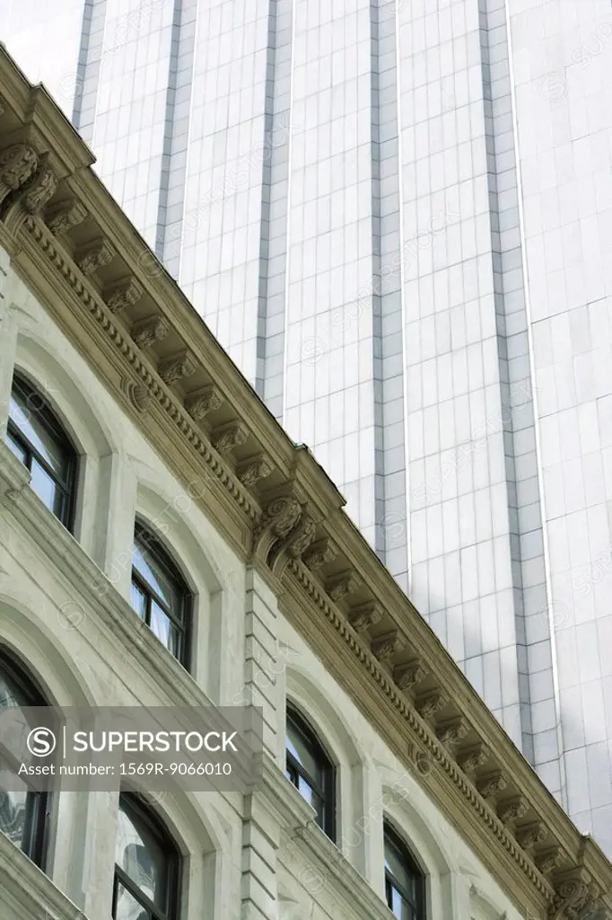 Facade of neoclassical building, modern skyscraper towering above, low angle view