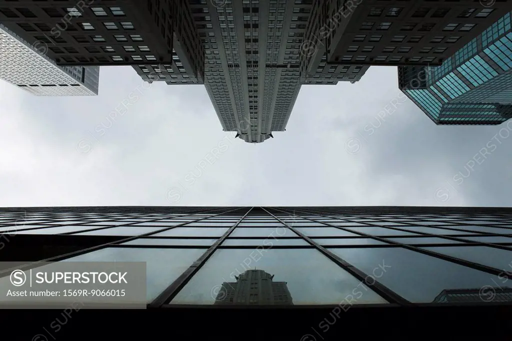 Reflection of skyscraper on glass facade of building on opposite side of street, viewed from below