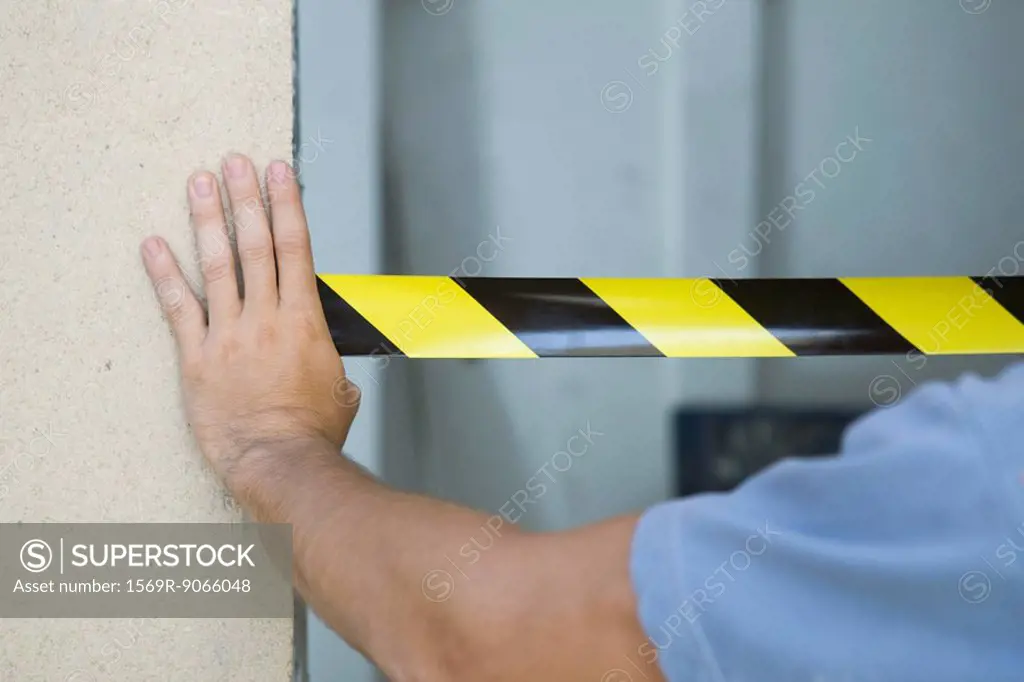 Worker placing safety tape across doorway