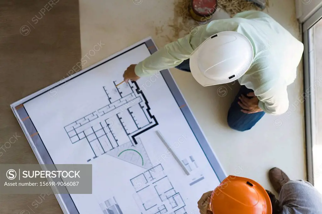 Two men reviewing blueprint spread out on floor