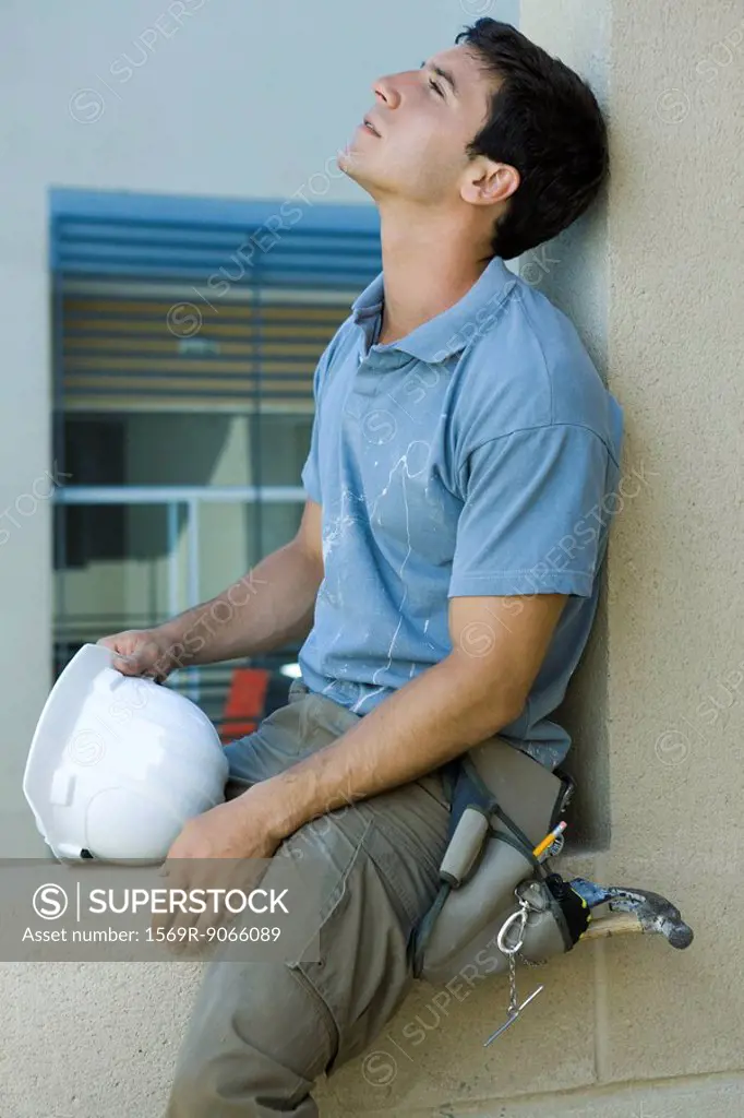 Man sitting on ledge, leaning head back, looking up