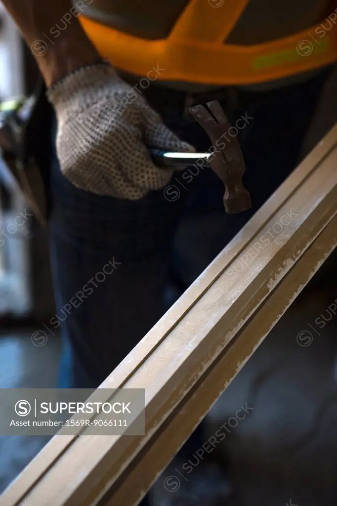 Worker holding hammer against wood