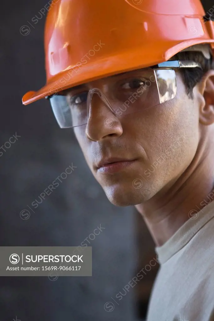 Construction worker wearing hard hat, protective glasses looking at camera