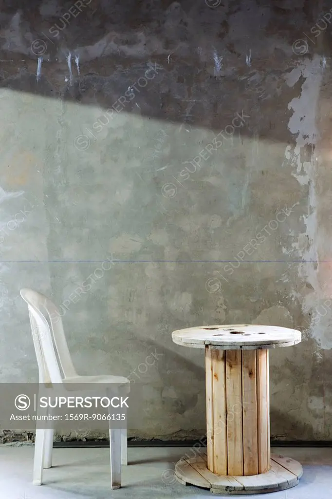 Plastic chair set before wooden reel table in unfinsihed room