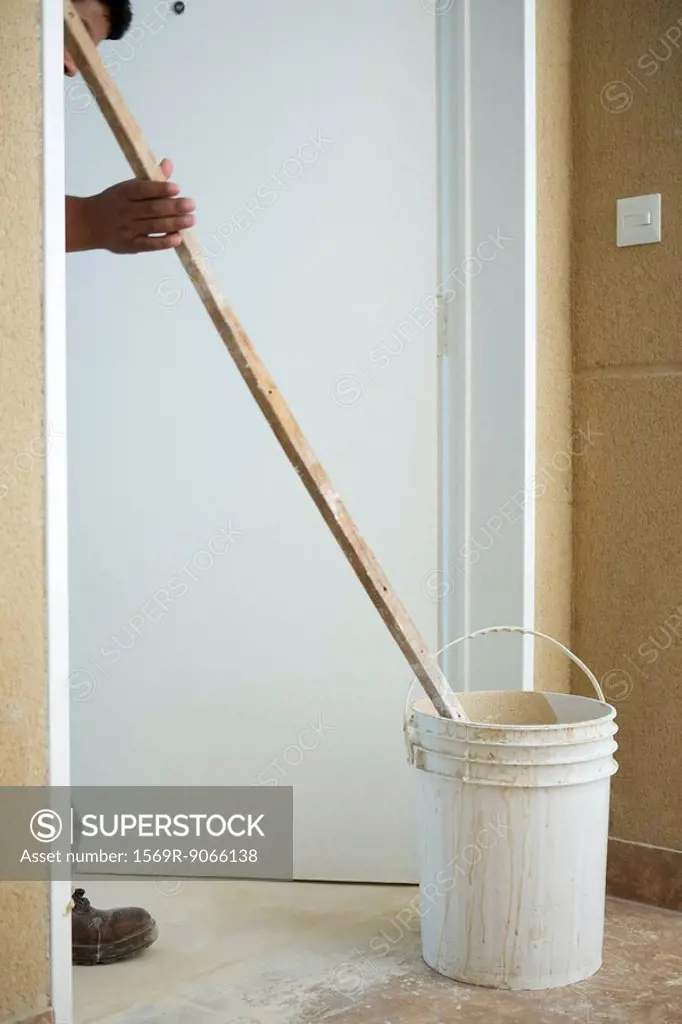 Worker mixing bucket of plaster